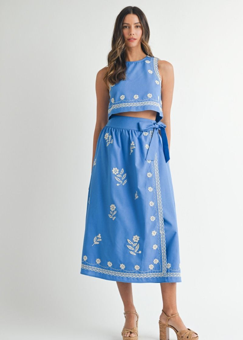 Woman wearing a blue embroidered outfit on a white background