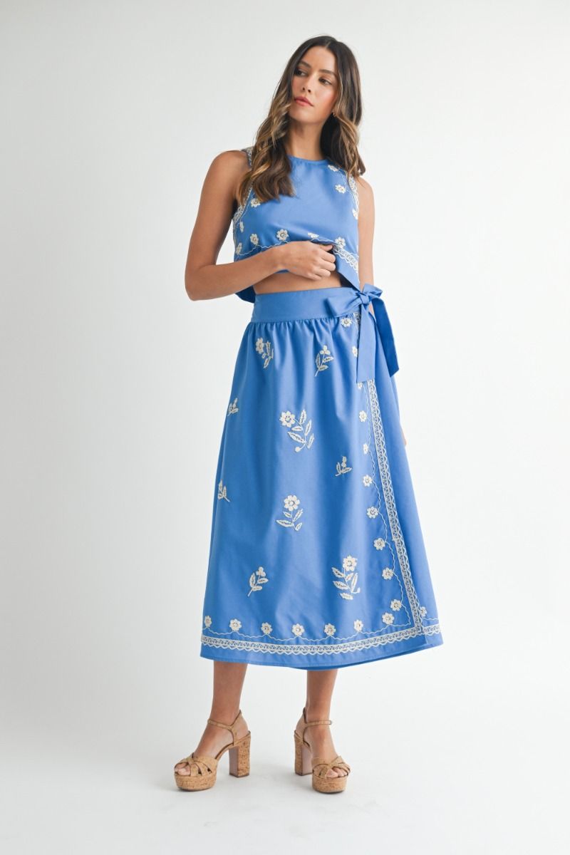 Woman wearing a blue embroidered dress on a white background